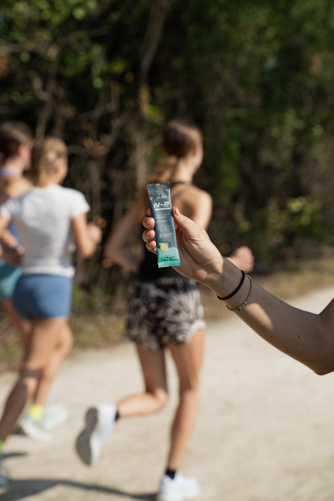 A runner hands off an N-2 mineral hydration stick on a trail run